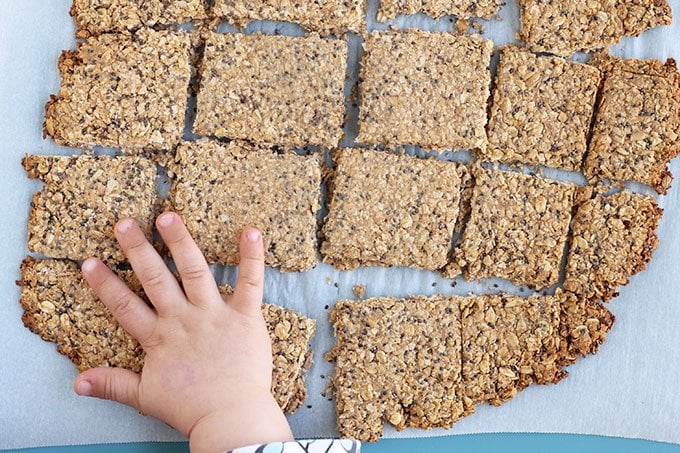 homemade granola bars on parchment with toddler hand