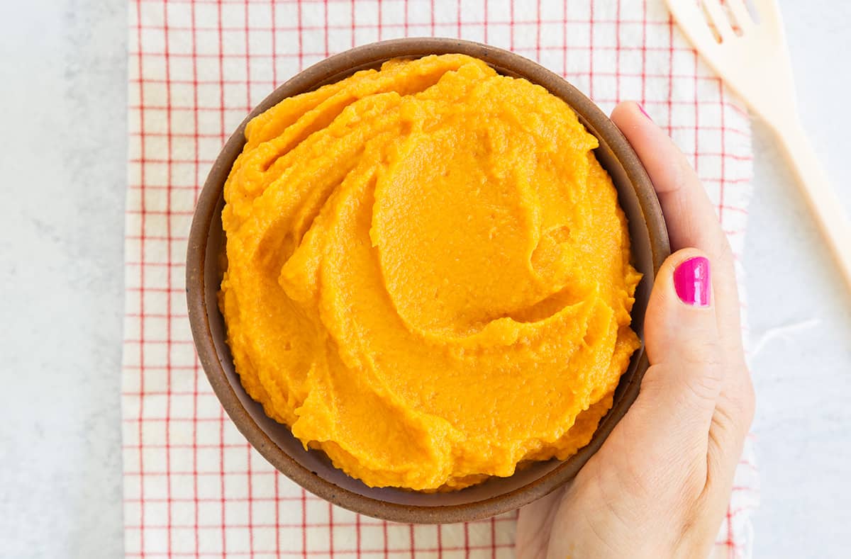 bowl of healthy mashed sweet potatoes in hand.