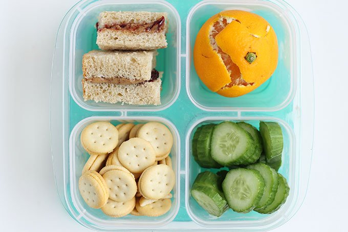 bento box with sandwich, clementine, crackers, cucumber