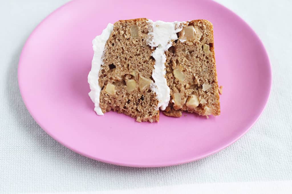 slice of healthy apple cake with frosting on pink plate