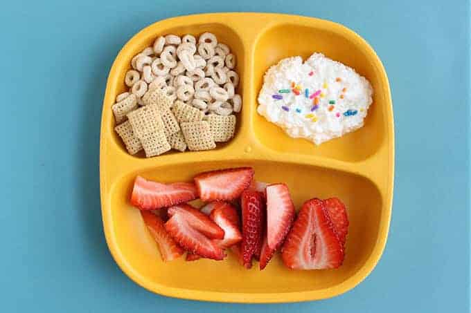 yellow kids breakfast plate with cereal, cottage cheese, and strawberries
